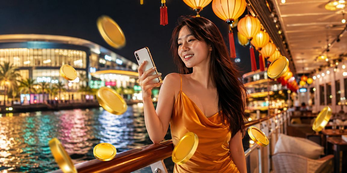 Cảnh chợ đêm Phú Quốc với người dùng kiểm tra ứng dụng thanh toán trên điện thoại